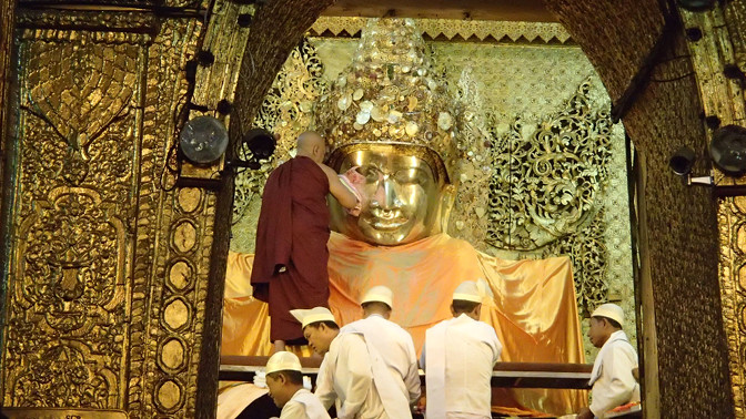 Monk dries Mahamuni Buddha's face