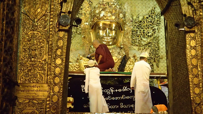 Monk applies resin and gold leaf to Mahamuni Buddha