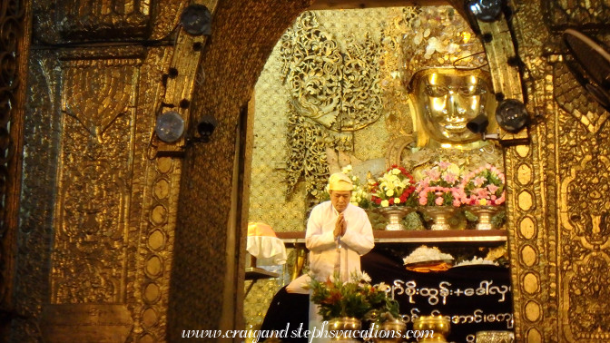 Attendant bows before Mahamuni Buddha