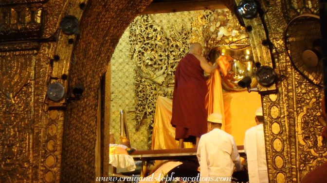 Monk covers Mahamuni Buddha with saffron cloth