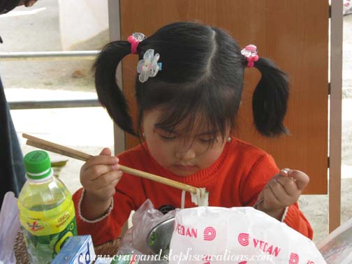 Toddler eating noodles at Dong Van market