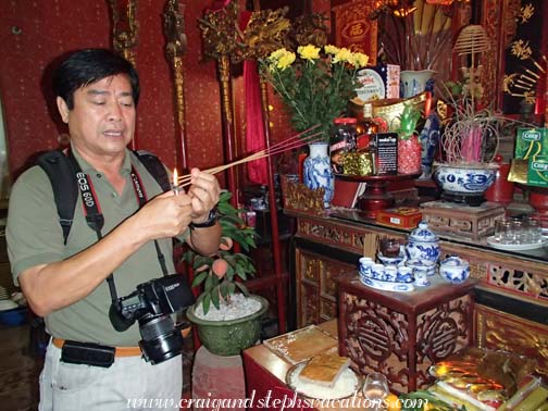 Cuong lighting incense at his family's ancestor altar