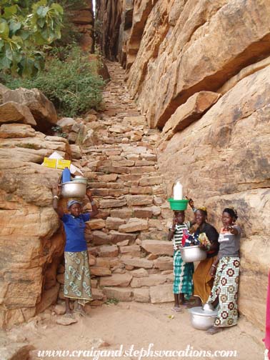 Dogon women approach the cliffside staircase