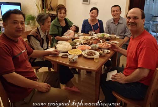 Dinner: Mr. Zhou, Wang Jun's mother Chen Rulan, Xiao Yi's mother Zhu Yongli holding Ziting, Xiao Yi, Wang Jun, and Craig