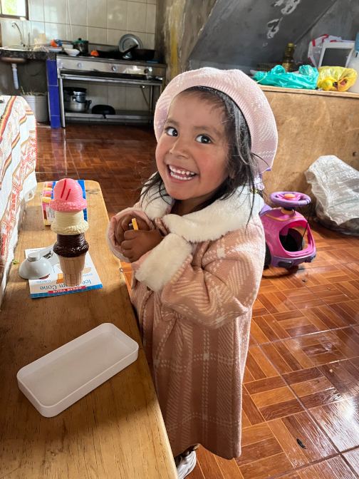 Nena wearing her new coat and hat, playing with her ice cream toys