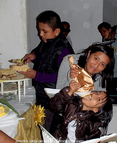 Junior cuts a piece of cake and Yasmin watches Aracely lick frosting from the cake topper