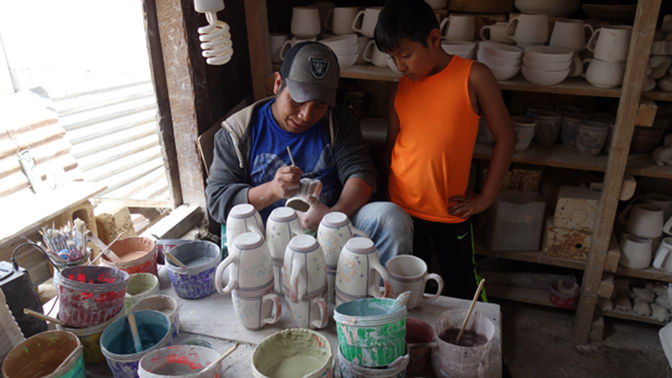 Eddy watches an artist effortlessly decorate the ceramics