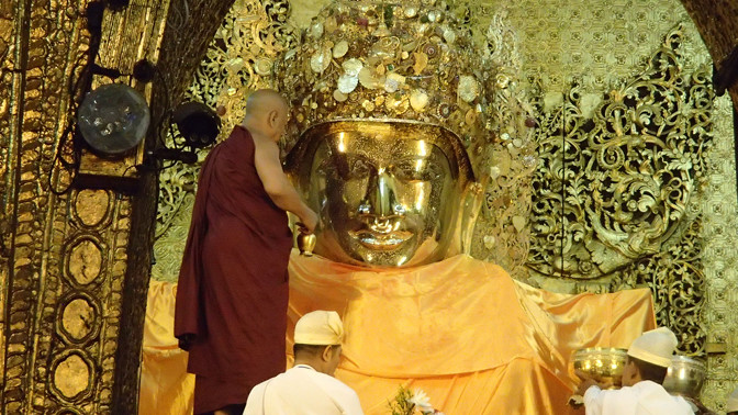 Monk spritzes Mahamuni Buddha's face with water