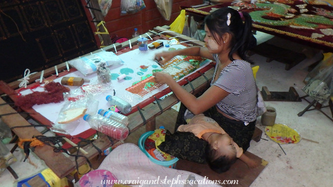 Mother embroiders a kalaga while her toddler sleeps, Aung Nan Handicrafts Workshop