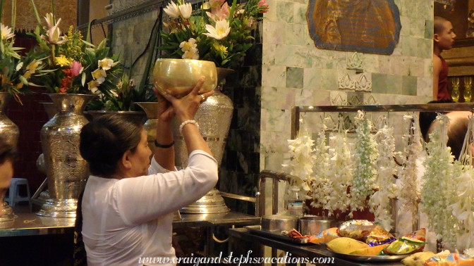 Attendant holds offerings up to the Mahamuni Buddha