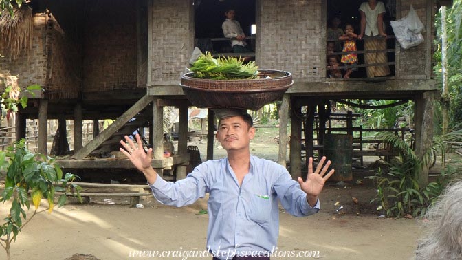 Sandro Win balances a basket on his head, Shwe Lat Pan Village