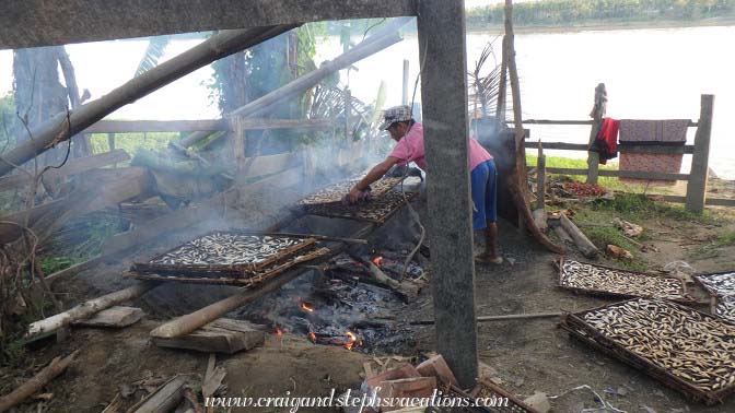 Smoking fish over a fire, Tha Phan Seit Village