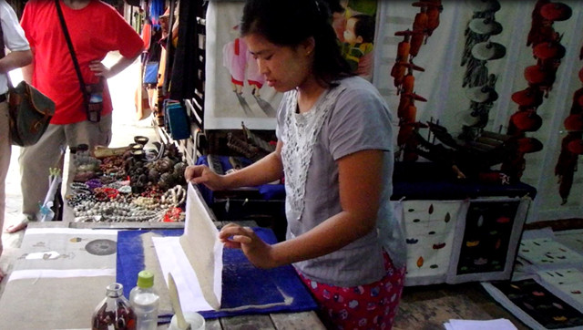 Sand artist applies Irrawaddy River sand to a cloth using acacia gum